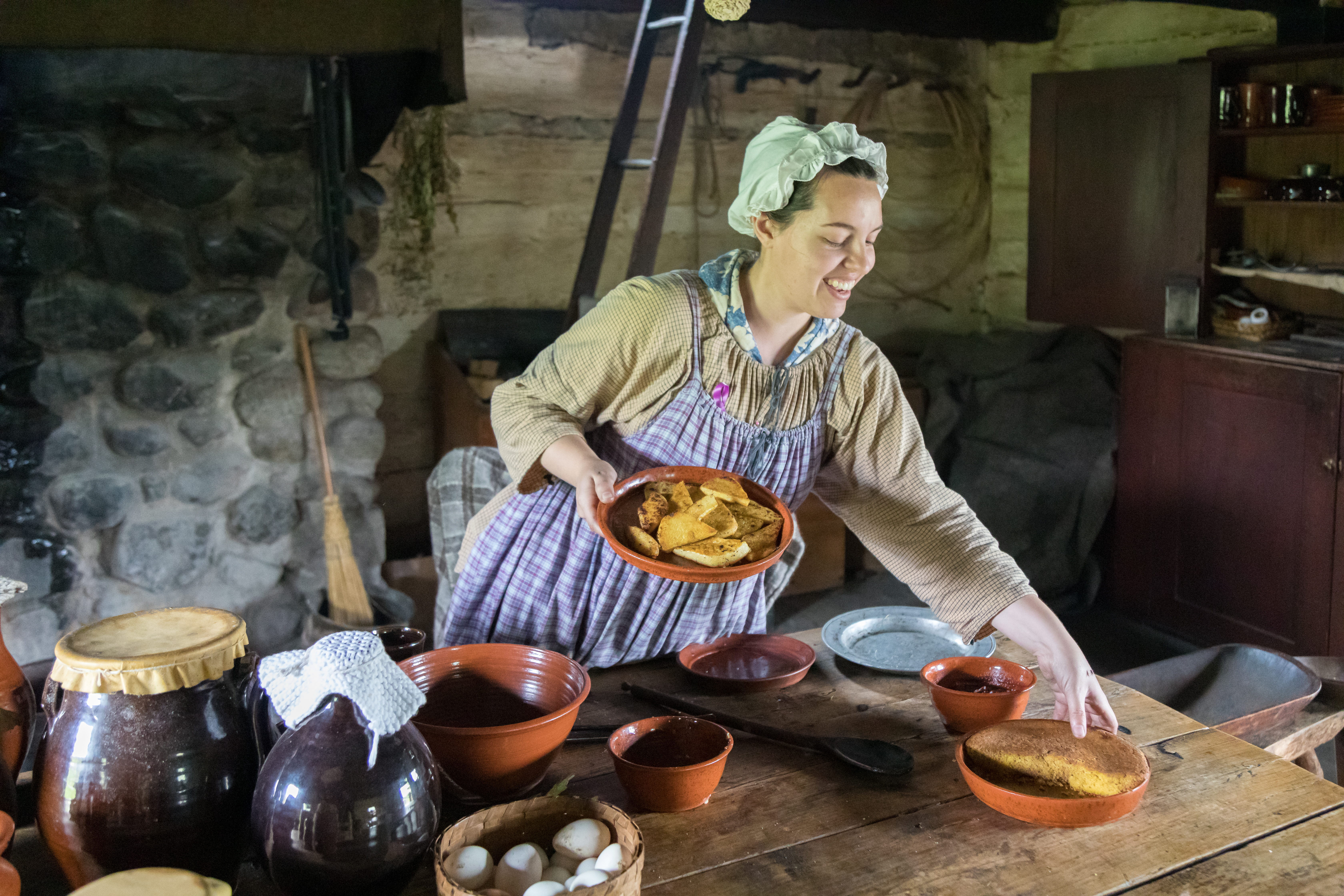 Woman in historic attire workngin a kitchen