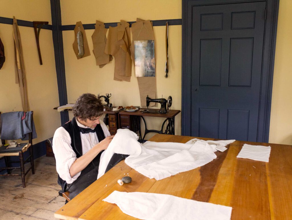 Man in historic attire sewing a garment